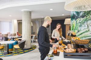 a man and a woman standing at a buffet in a restaurant at Aparthotel Adagio Birmingham City Centre in Birmingham