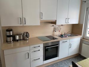 ノルダーナイにあるStrandflieder Backbordの白いキャビネットとシンク付きのキッチン