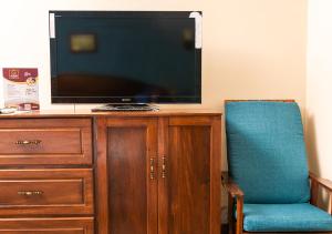 un televisor sentado en la parte superior de un armario de madera con una silla azul en Mansión Los Guichos, en Retalhuleu