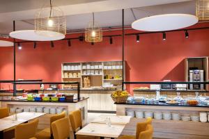 a restaurant with red walls and tables and chairs at SOWELL RESIDENCES Chênes Verts in Saint-Raphaël
