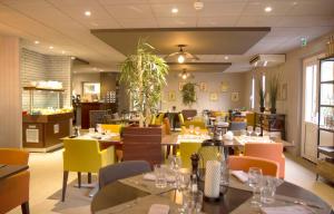 um restaurante com mesas e cadeiras com cadeiras amarelas e laranjas em Best Western The Hotel Versailles em Buc