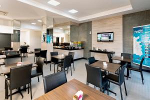 um restaurante com mesas e cadeiras e uma cozinha em Hotel Valerim Itajaí / Navegantes em Itajaí
