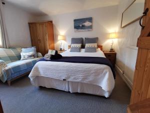 een slaapkamer met een groot bed met een kat erop bij AnchorageWells Entire Cottage or King Ensuite Rooms in Wells next the Sea