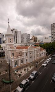 um grande edifício branco com carros estacionados num parque de estacionamento em Hotel Valerim Itajaí / Navegantes em Itajaí