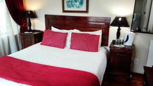 Un dormitorio con una cama con dos almohadas rojas. en The Riverhouse Guesthouse, en Estcourt
