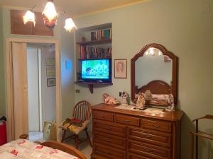 a bedroom with a dresser with a mirror and a television at Guest House Brandino Pani in Tertenìa