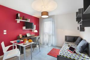 a small living room with a red accent wall at Résidence Nemea Clermont Centre in Clermont-Ferrand