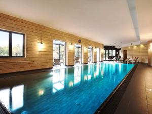 a large swimming pool with blue water in a building at VacationClub – Dworcowa 1A Apartament 3 in Szklarska Poręba