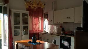 a kitchen with white cabinets and a wooden table with chairs at Appartamento Balconcino su Lazise in Lazise