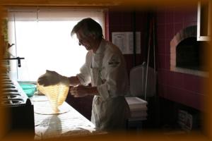 un hombre de pie en una cocina preparando comida en una cocina en Gasthof zum Schlern, en Fiè