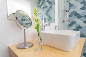 a bathroom with a sink and a mirror and a vase with flowers at DonaCamó Charming House in Nazaré