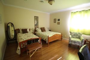 1 dormitorio con 2 camas, silla y espejo en The Fiddle and the Sea Bed and Breakfast, en Port Hood