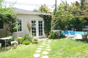 a yard with chairs and a table and a house at Culver City Escape with Pool, Near Disneyland Park! in Los Angeles