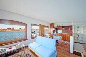 ein Wohnzimmer mit einem blauen Sofa und einer Küche in der Unterkunft DolceVita Apartments N 453 Canal View in Venedig