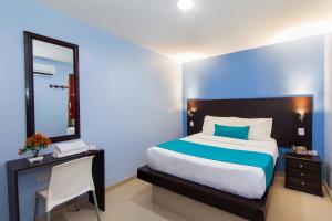 a bedroom with a bed and a dresser at Azuán Suites Hotel By GH Suites in Cartagena de Indias