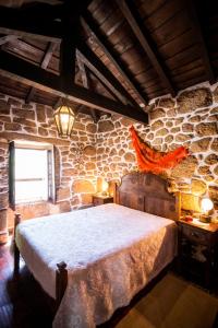 a bedroom with a large bed in a stone wall at Moinho de Estoraos in Ponte de Lima