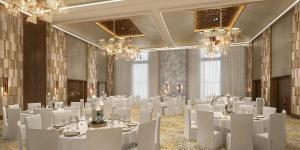 a banquet hall with white tables and chairs and chandeliers at Holiday Inn Dubai Al-Maktoum Airport by IHG in Dubai +51 photos