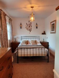 1 dormitorio con 1 cama con lámpara de araña encima en The Mews, Talley, en Llandeilo