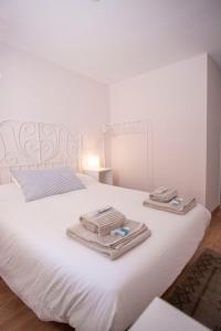 ein Schlafzimmer mit einem weißen Bett und Handtüchern darauf in der Unterkunft Apartamento Dúplex Casco Antiguo AT Postigo 20 in Cáceres