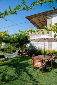 una mesa de picnic y un banco con sombrilla en Casa do Ribeiro, en Guimarães