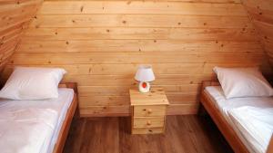 a bedroom with two beds and a night stand with a lamp at Wantaris - domki letniskowe z ogródkiem Mielno-Mielenko in Mielno