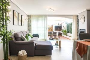 ein Wohnzimmer mit Sofa und Tisch in der Unterkunft Bungalow Altea junto al casco antiguo, piscina y barbacoa in Altea