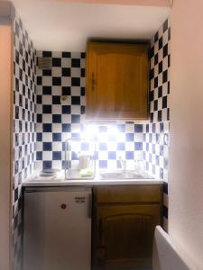 a small kitchen with a sink and a checkered wall at Boost Your Immo Duplex Les Deux Alpes 272 in Les Deux Alpes