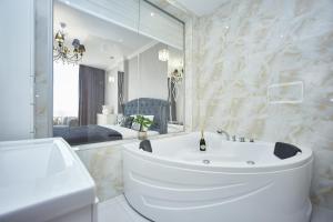 a white bathroom with a tub and a mirror at Arcadia Promenade Grand Apartments in Odesa