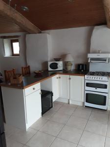 cocina con armarios blancos y fogones en La Galerne, en Montpellier-de-Médillan