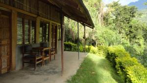 a porch of a house with a table and chairs at Ruboni Community Camp in Kasese