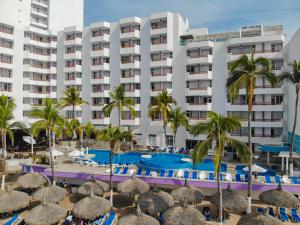 a hotel with a swimming pool and palm trees at Oceano Palace in Mazatlán