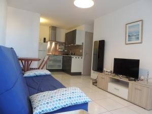 a living room with a blue couch and a kitchen at Cathymini à Sete in Sète