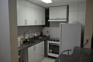 a kitchen with white cabinets and a white refrigerator at AP532 Thermas Paradise Cobertura Duplex 2 quartos in Rio Quente