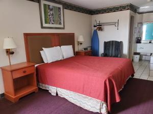 a hotel room with a red bed and a chair at Americas Best Value Inn Wildersville in Wildersville
