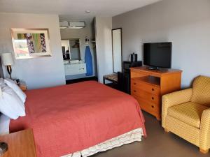 a hotel room with a bed and a tv and a chair at Americas Best Value Inn Wildersville in Wildersville