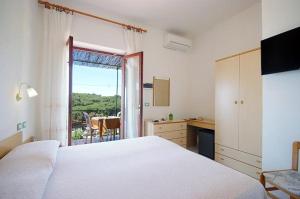 una camera con un letto bianco e una finestra di Hotel Alma a Campo nell'Elba