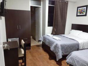 a hotel room with two beds and a chair at ORBEGOSO - Trujillo in Trujillo