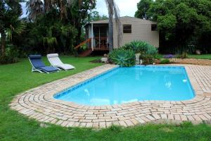 a swimming pool in a yard with two chairs and a house at Bietjie Rus in Addo