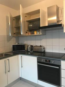 une cuisine avec des armoires blanches et des appareils noirs dans l'établissement Mazotos 54m2 One Bedroom Flat, "Panoramic Village", à Mazotos