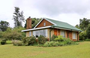 a house with a green roof on a yard at Lakeview Cottages in Haenertsburg