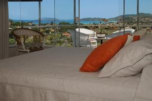 1 cama con almohadas de color naranja en la parte superior de un balcón en Casa em Búzios "A Curva do Sol", en Búzios