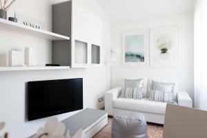 een woonkamer met een witte bank en een flatscreen-tv bij Fly by Suites Pescara in Pescara