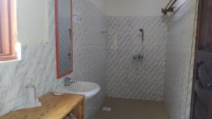 a white bathroom with a sink and a shower at The Elephant Home in Katunguru
