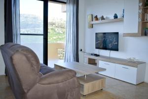 a living room with a chair and a television at Cesca Apartments - Marsalforn, GOZO in Marsalforn