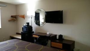 - une chambre avec un bureau et une télévision murale dans l'établissement Super 8 by Wyndham Greenville, à Greenville