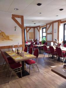 uma sala de jantar com mesas e cadeiras vermelhas em Pension & Gasthaus Kattenstieg em Kattenstiegs-Mühle