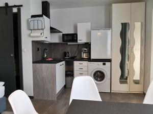a kitchen with white cabinets and a washer and dryer at Apartamenty Jaskinia Solna in Ruda Śląska