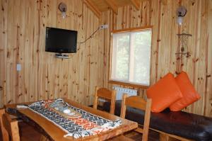 a living room with a table and a television and a couch at Parajes del lejano sur cabaña El Cardo in Moquehue