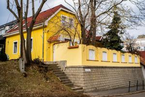 une maison jaune avec un mur en briques et des escaliers dans l'établissement Szitakötő Apartman, à Eger