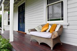 einen Korbstuhl mit Kissen auf einer Veranda in der Unterkunft Harold House in Reefton